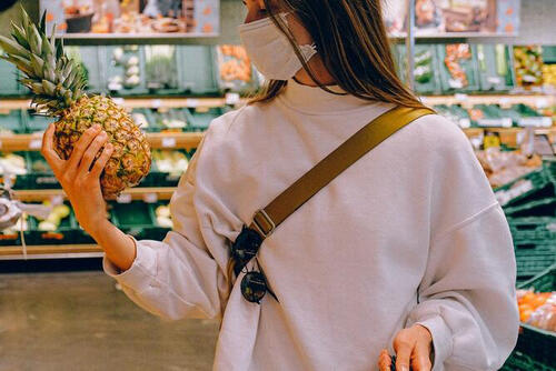 woman looking at pineapple in grocery aisle