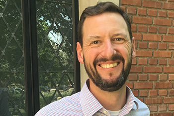 olstead in front of a building smiling