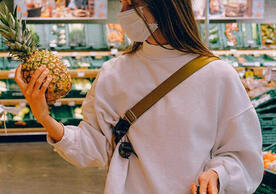 woman looking at pineapple in grocery aisle